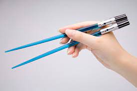 Hand holding blue space-themed chopsticks with black detailing.